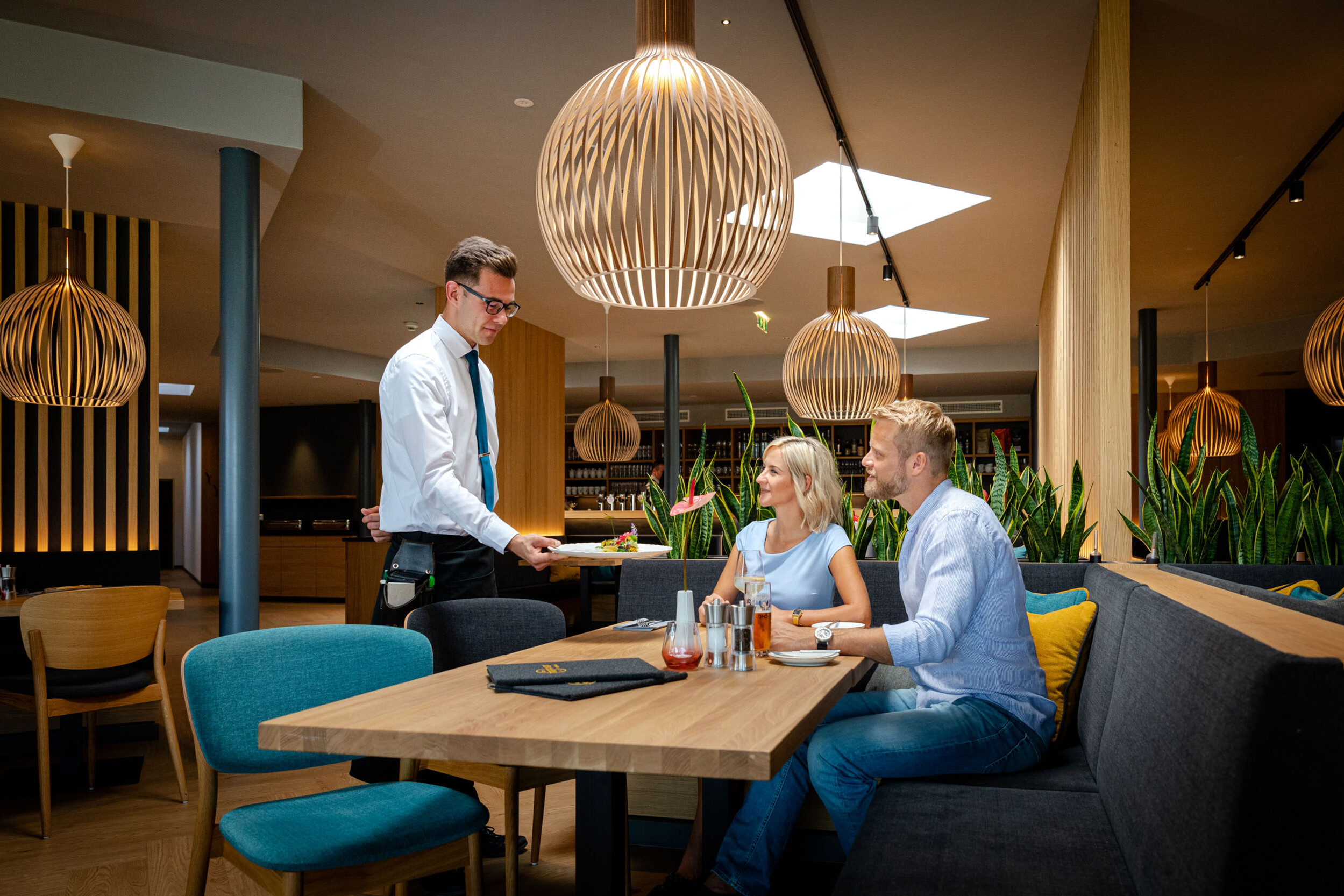 Der Kellner serviert einem Paar im familiären Hotel eduCARE in Kärnten ihr Essen