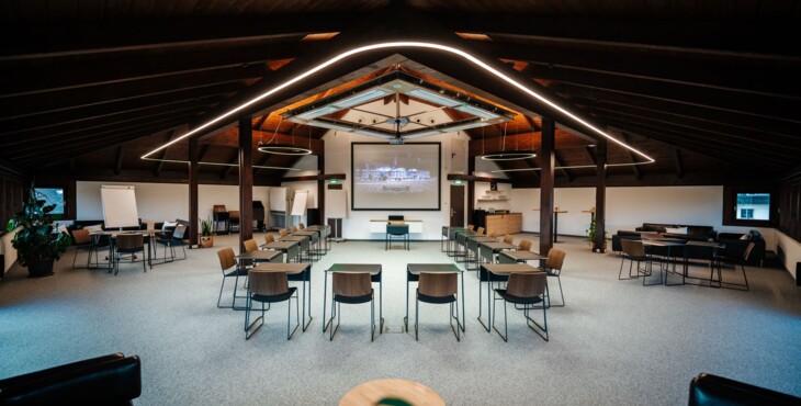 Ein moderner Konferenzraum mit Stühlen, Tischen und einem großen Bildschirm an der Wand, ideal für Meetings und Präsentationen.