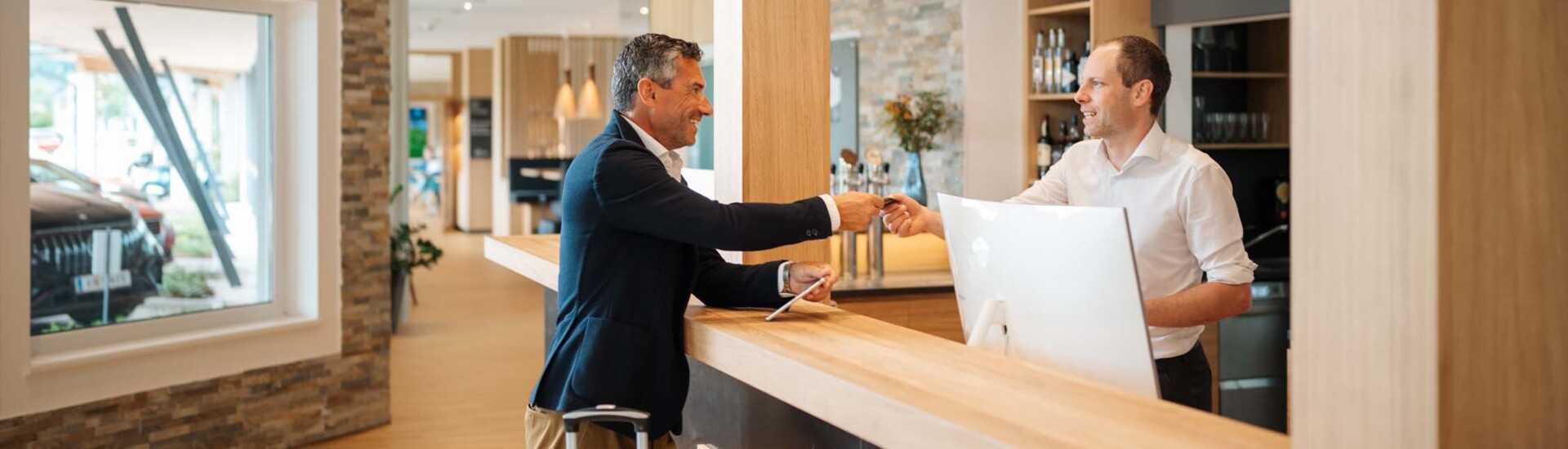 Ein Empfangsmitarbeiter überreicht einem Mann die Zimmerkarte an der Rezeption.