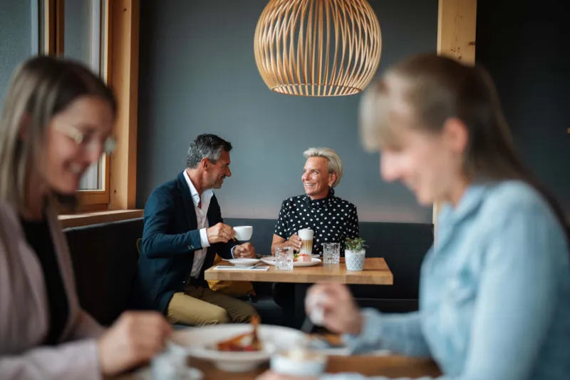 Personen trinken einen Kaffee im Restaurant, lächelnd und im Gespräch vertieft.