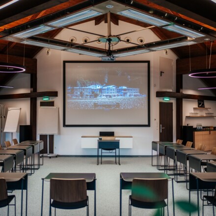 Moderner Seminarraum mit Projektor und Tischen in U-Form.