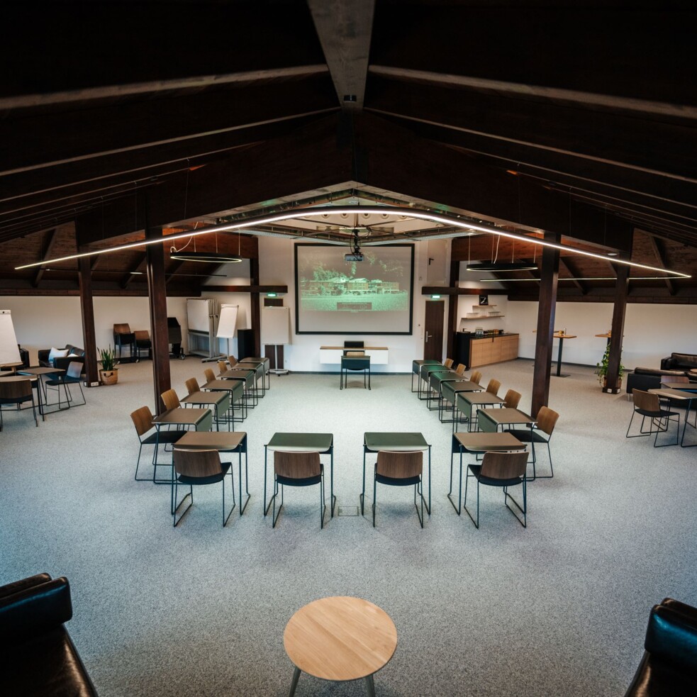 Ein moderner Seminarraum mit Stühlen und Tischen in U-Form, Projektor und Flipchart, ideal für Workshops und Präsentationen.