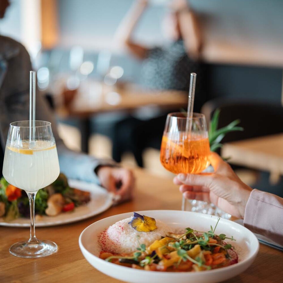 A table with two drinks and a colorful dish garnished with flowers, set in the ambiance of restaurant "Zum Treffner"