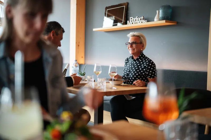 Frau sitzt in Restaurant und genießt eine Mahlzeit und trinkt dazu Wein.