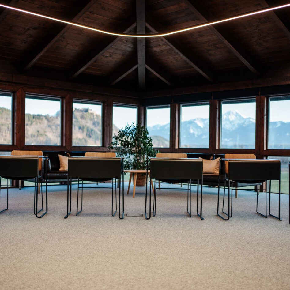Ein moderner Seminarraum mit Blick auf die umliegende Berglandschaft aus den Panoramafenstern. 