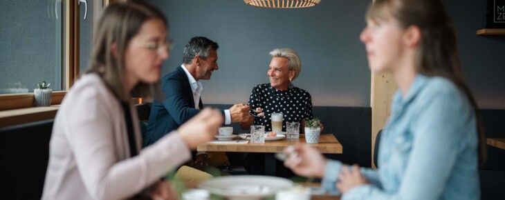 Personen unterhalten sich im Restaurantbereich des Hotels bei Getränken.