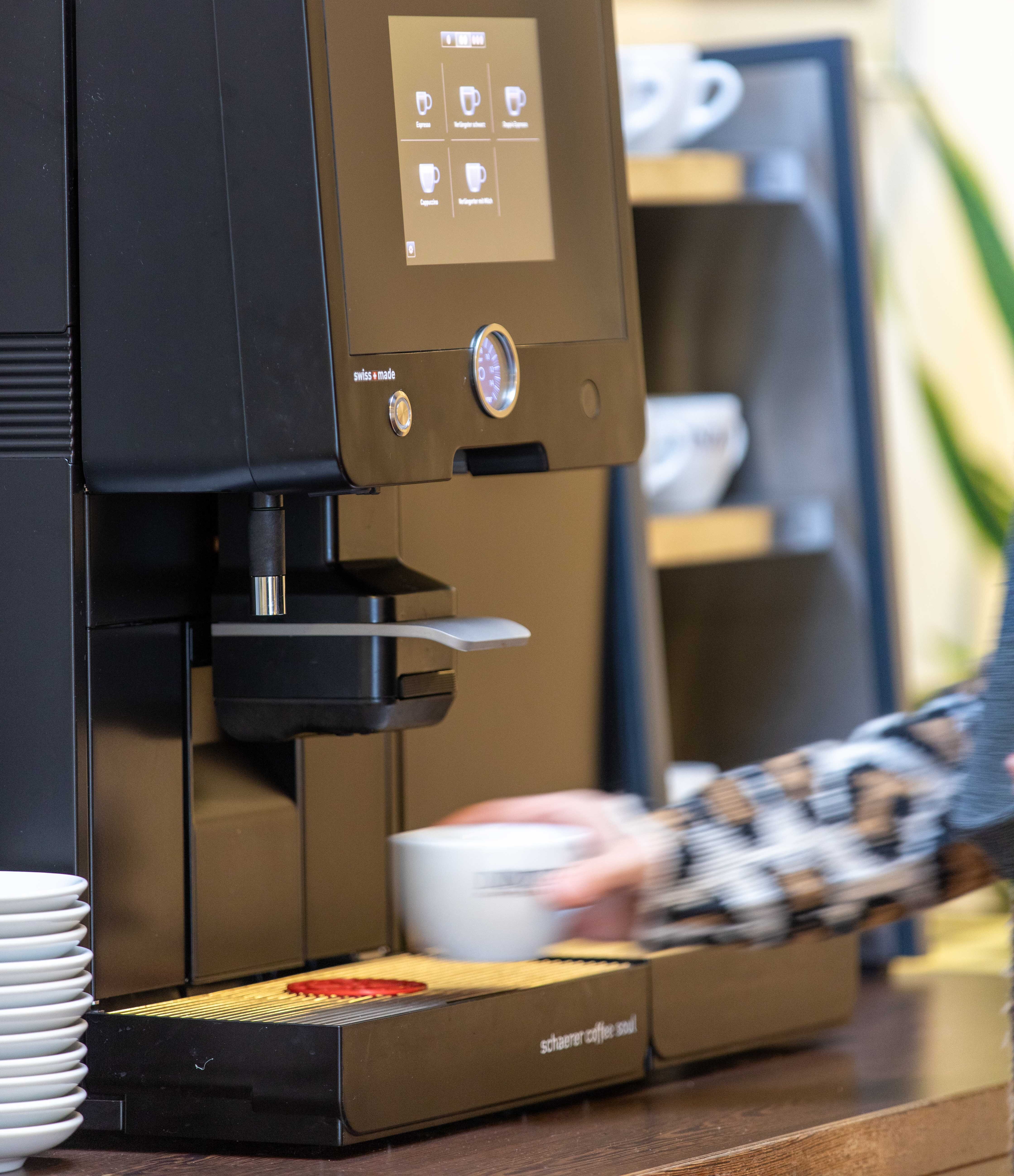 Eine Person bedient einen modernen Kaffeevollautomaten.