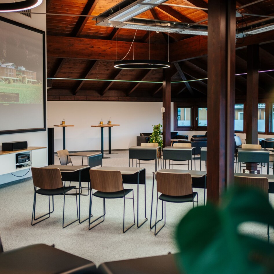 Moderner Konferenzraum mit Leinwand, Stühlen und Holzdecke.