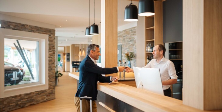 Ein Empfangsmitarbeiter überreicht einem Mann die Zimmerkarte an der Rezeption.