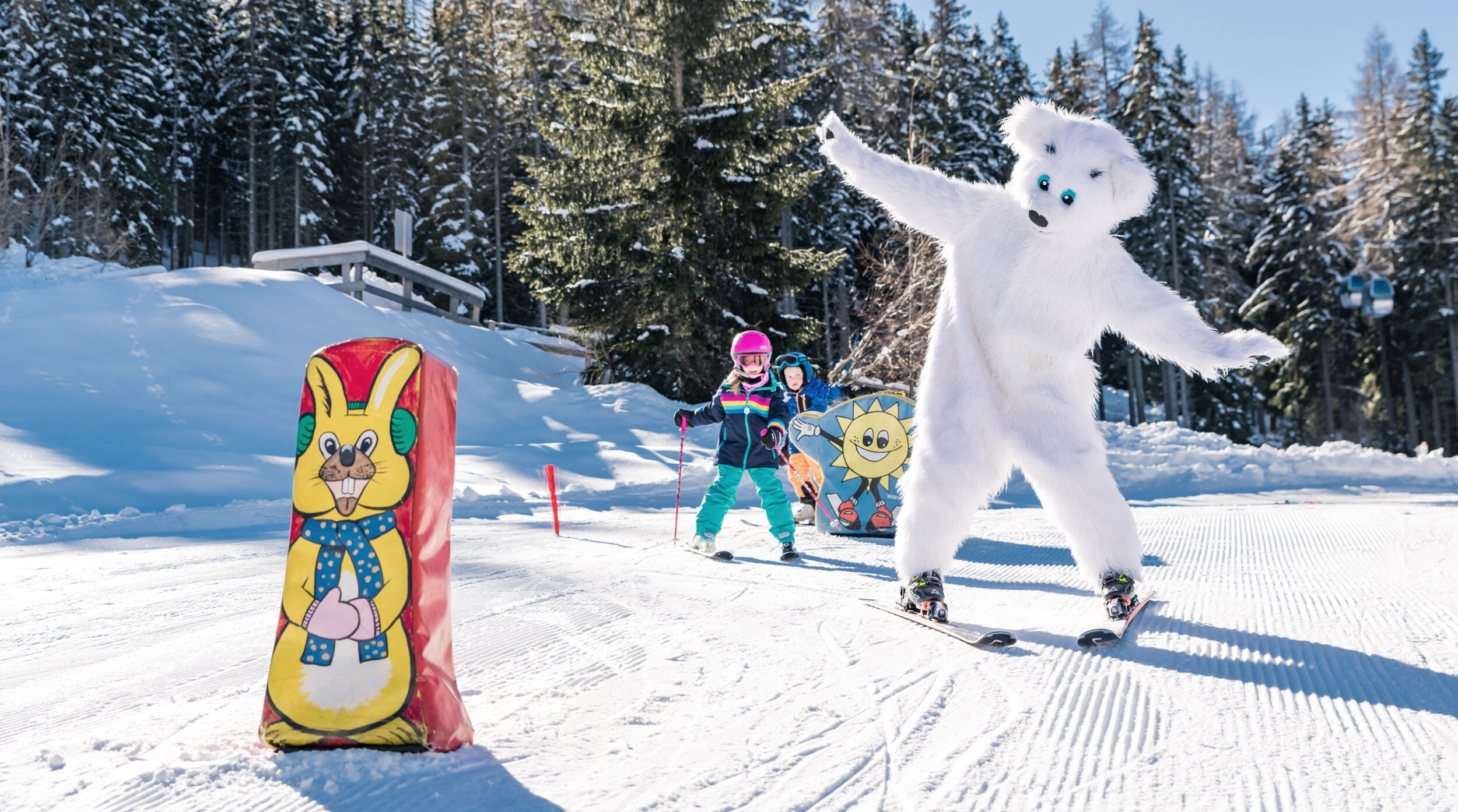 A child skis on the practice area on the Gerlitzen Alpe. The region's mascot Bino Bear is also skiing.