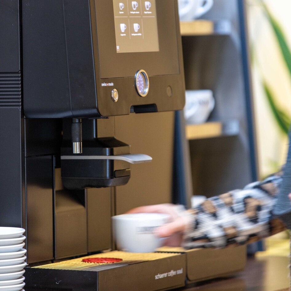 Eine Person bedient einen modernen Kaffeevollautomaten.