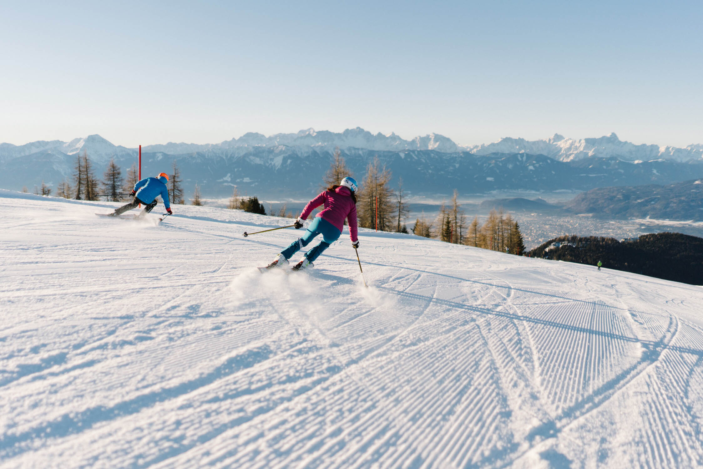 Zwei Personen fahren Ski auf einer verschneiten Piste auf der Gerlitzen Alpe in Kärnten.