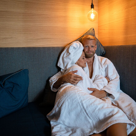 Ein Paar liegt im gemütlichen Ruhebereich des Wellnessbereichs vom Hotel eduCARE in Treffen am Ossiacher See