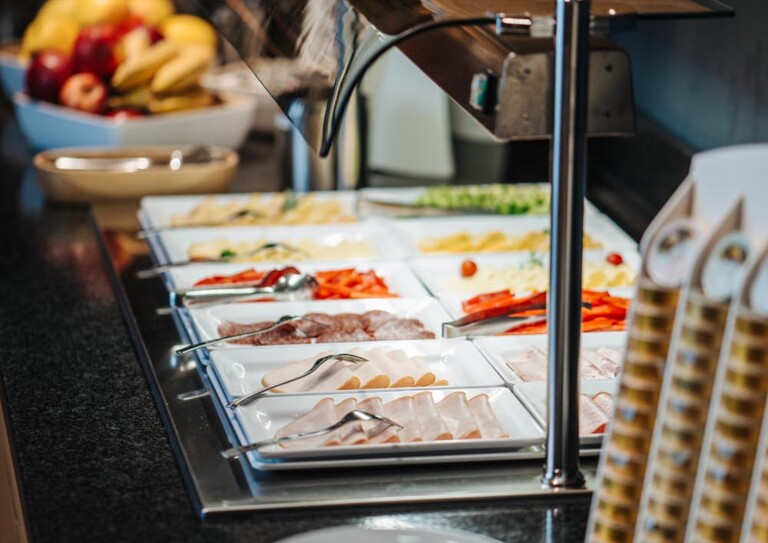 Ein reichhaltiges Frühstücksbuffet mit Aufschnitt, Gemüse und Obst in einem stilvollen Ambiente.
